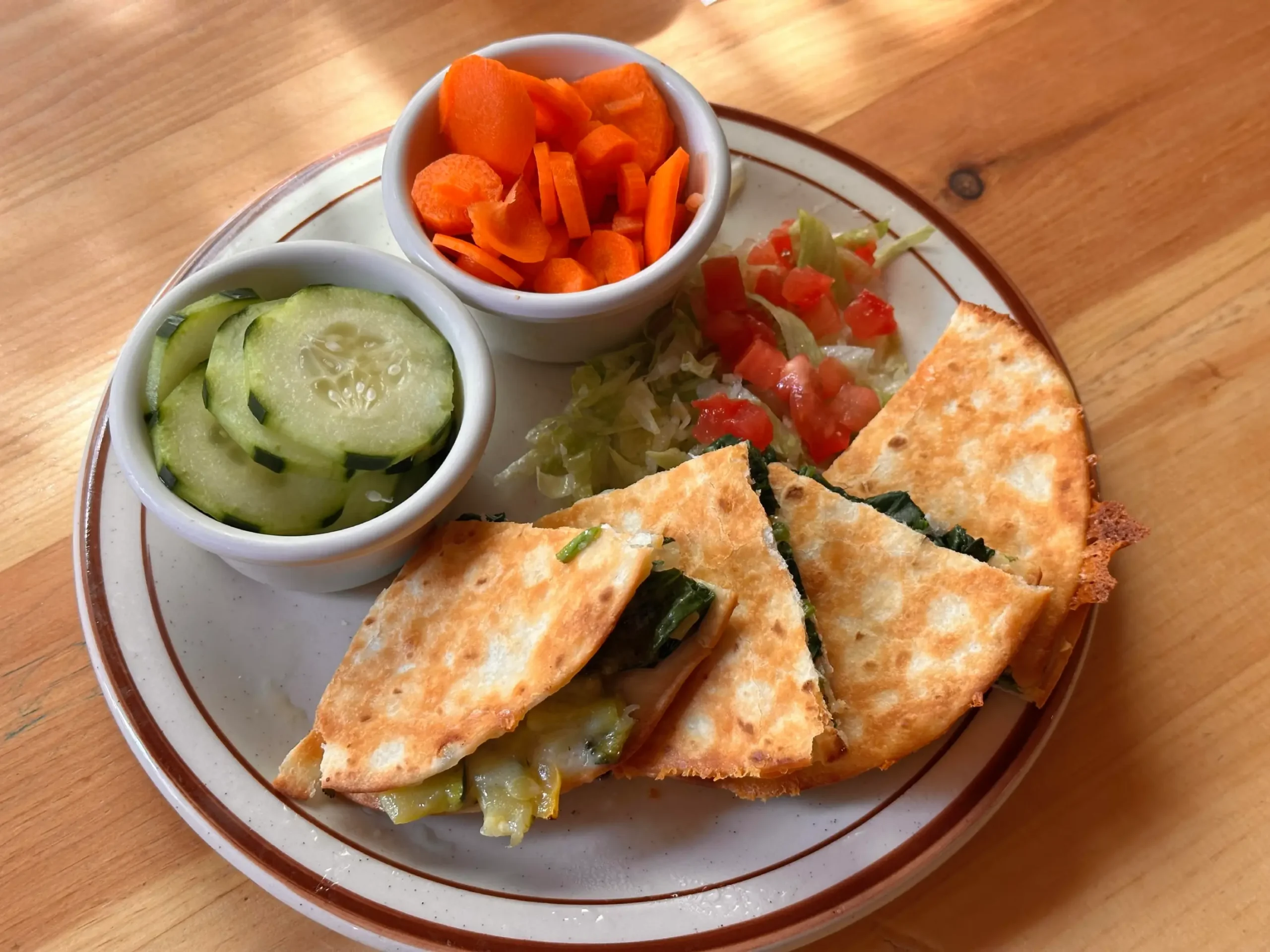 Overhead shot of veggie quesadilla and raw carrots and cucumbers
