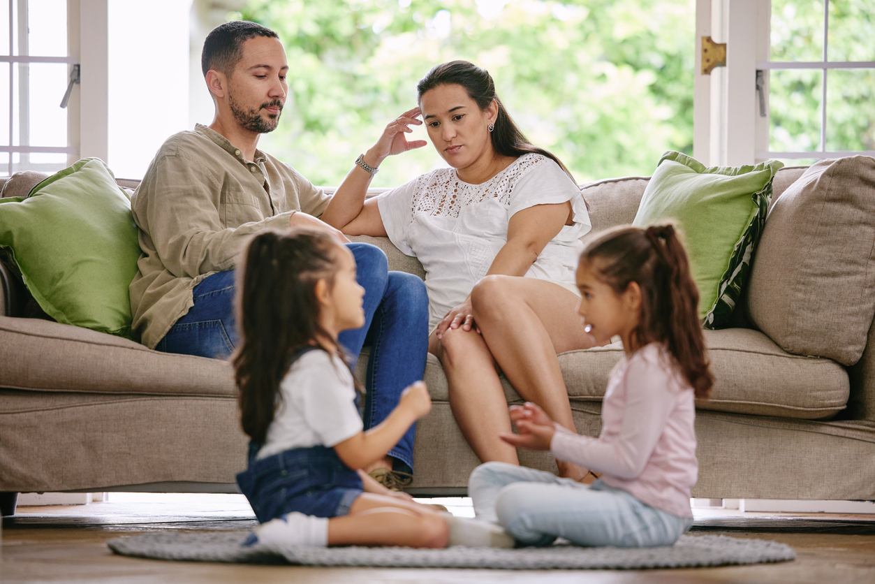 Two girls playing while their parents talk